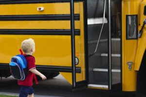 kleiner Junge geht auf Schulbus zu