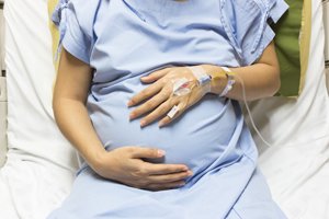 schwangere Frau mit Zugang im Krankenhausbett