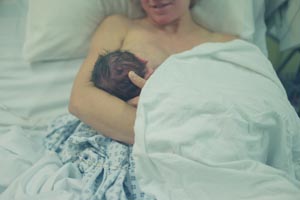junge Mutter stillt Neugeborenes