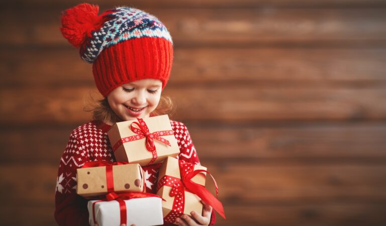 Kind mit Weihnachtsgeschenken im Arm