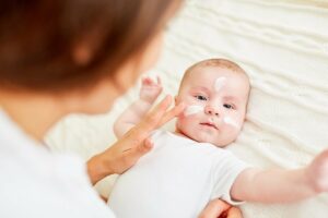 Junge Frau cremt ihrem Baby das Gesicht ein