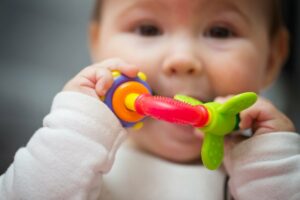 Kind nimmt Babyspielzeug in den Mund