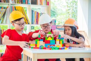 drei Kinder bauen gemeinsam mit Bauklötzen
