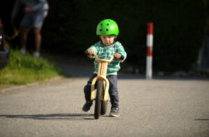 Kind fährt mit einem Laufrad aus Holz