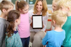 eine lehrerin zeigt kindern in der grundschule ein tablet