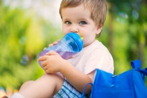 ein kleiner Junge trinkt Wasser aus einer Nuckelflasche