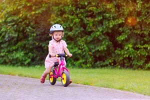 Mädchen fährt auf einem pinken Laufrad