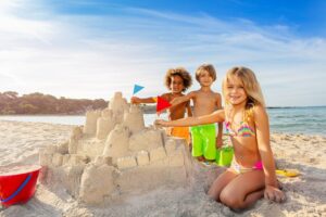 Kinder bauen gemeinsam eine Sandburg am Strand