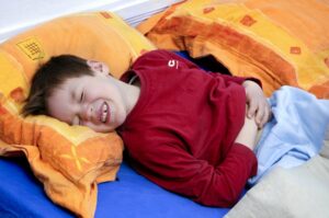 Kinder liegt mit schweren Bauchkrämpfen im Bett